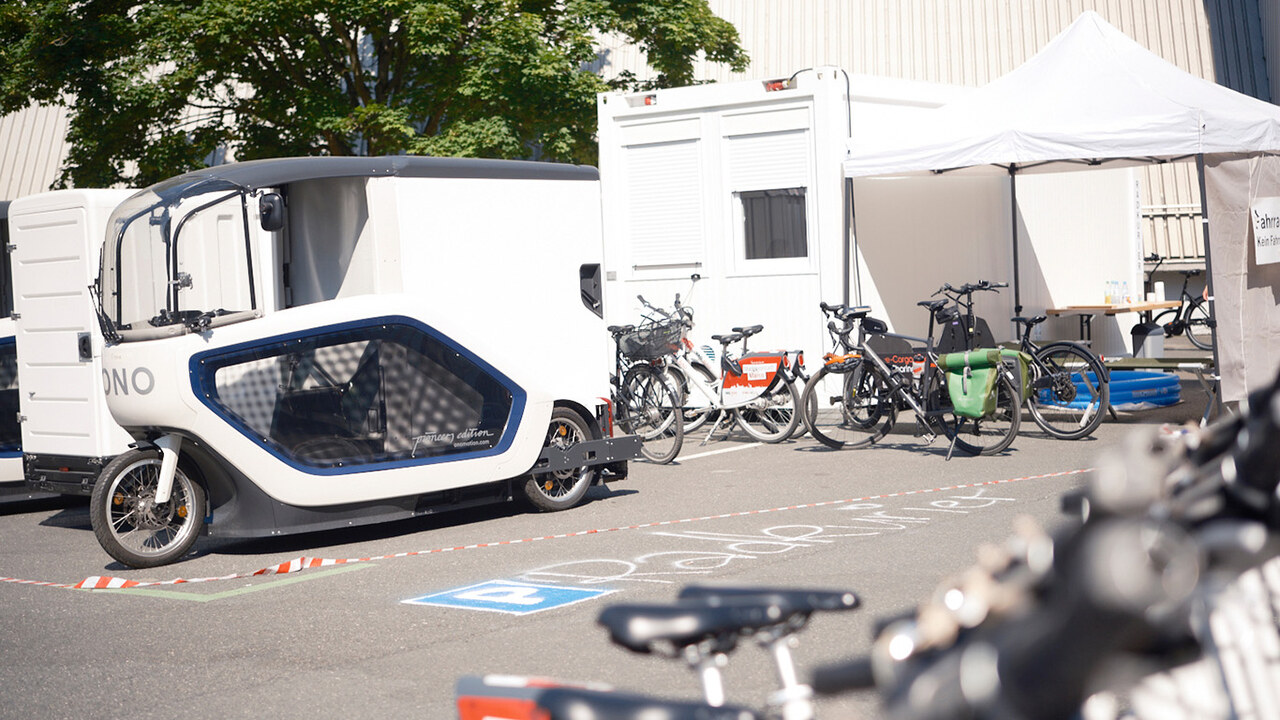 Fahrräder verschiedener Formen und Größen auf einem Parkplatz, mit Kreide steht "Radkurier" auf dem Boden