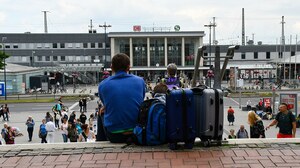 Mann mit Koffern vor Bahnhof