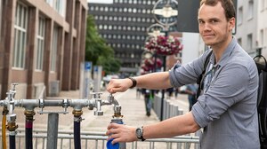 Junger Mann füllt Wasser in seine Flasche